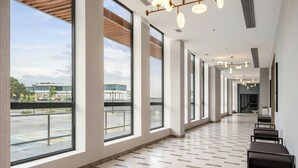 A spacious corridor with large windows, a tiled floor, and modern lighting fixtures. - Courtyard Cheddi Jagan International Airport, Guyana (Timehri)
