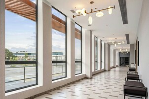 Un pasillo amplio con ventanas grandes, suelo de baldosas e iluminación moderna.