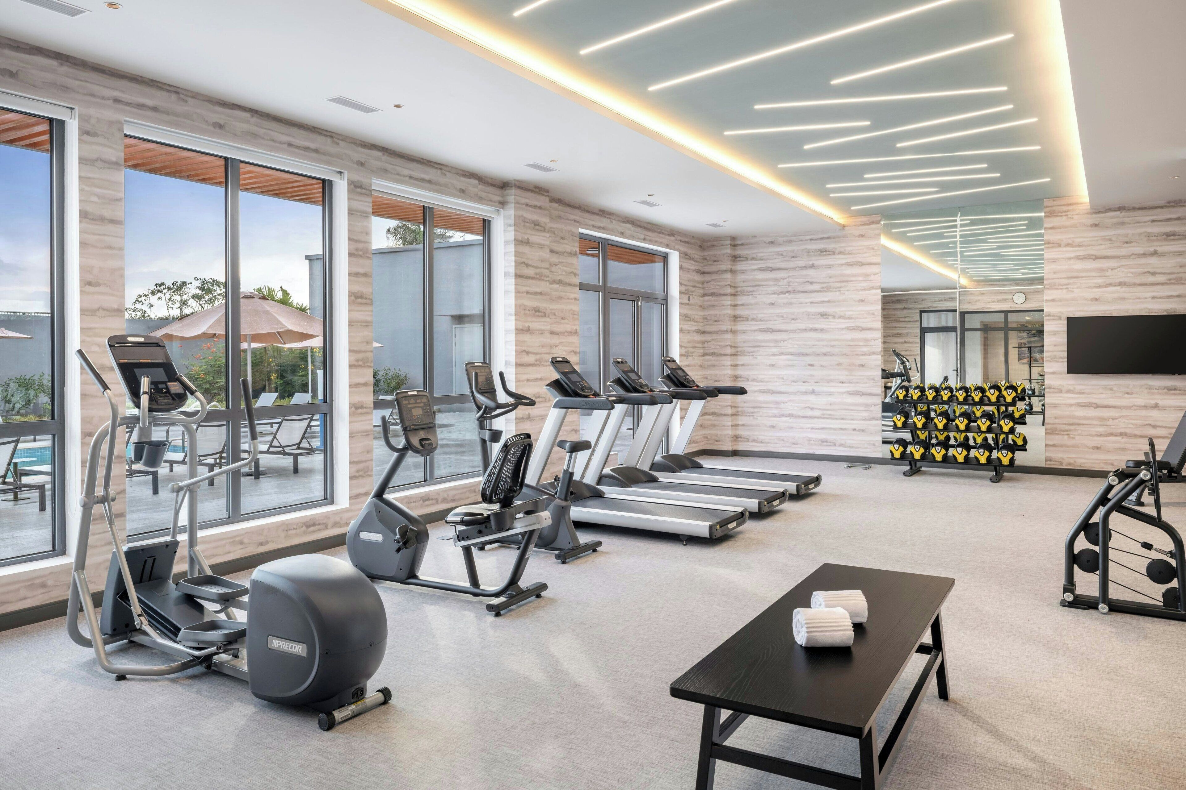Un gimnasio moderno con cintas de correr, elípticas y pesas libres.