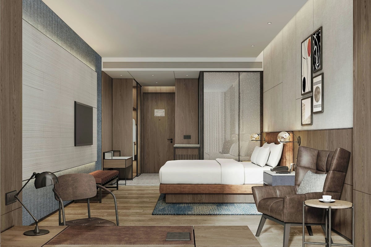 Une chambre d’hôtel moderne équipée d’un grand lit, d’un bureau, d’une chaise et d’une petite table.
