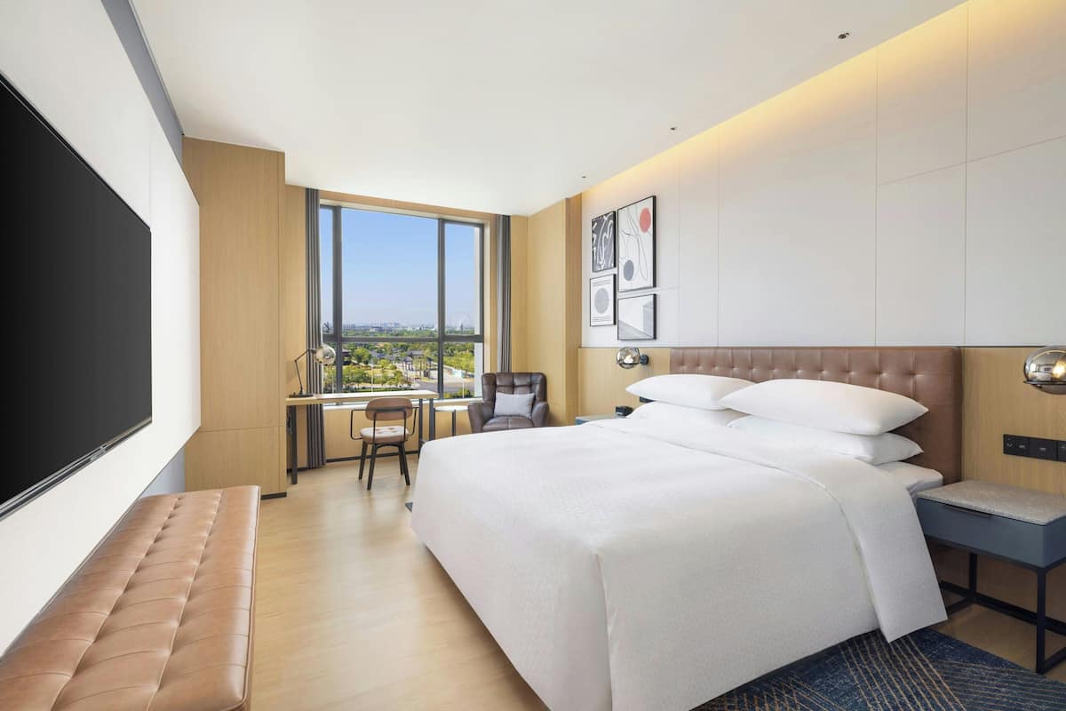 Une chambre d’hôtel moderne avec un grand lit, un bureau et une vue sur la ville.