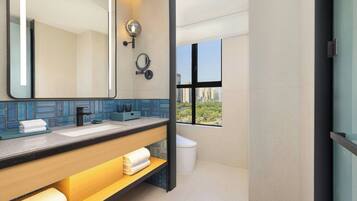 Un baño moderno con un espejo grande, lavamanos dobles y ventana con vista a la ciudad.