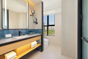 Un baño moderno con un espejo grande, lavamanos dobles y ventana con vista a la ciudad.