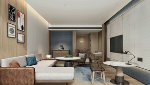 Une chambre d’hôtel moderne équipée d’un canapé, d’une table à manger ronde, d’une chaise et d’un téléviseur fixé au mur.