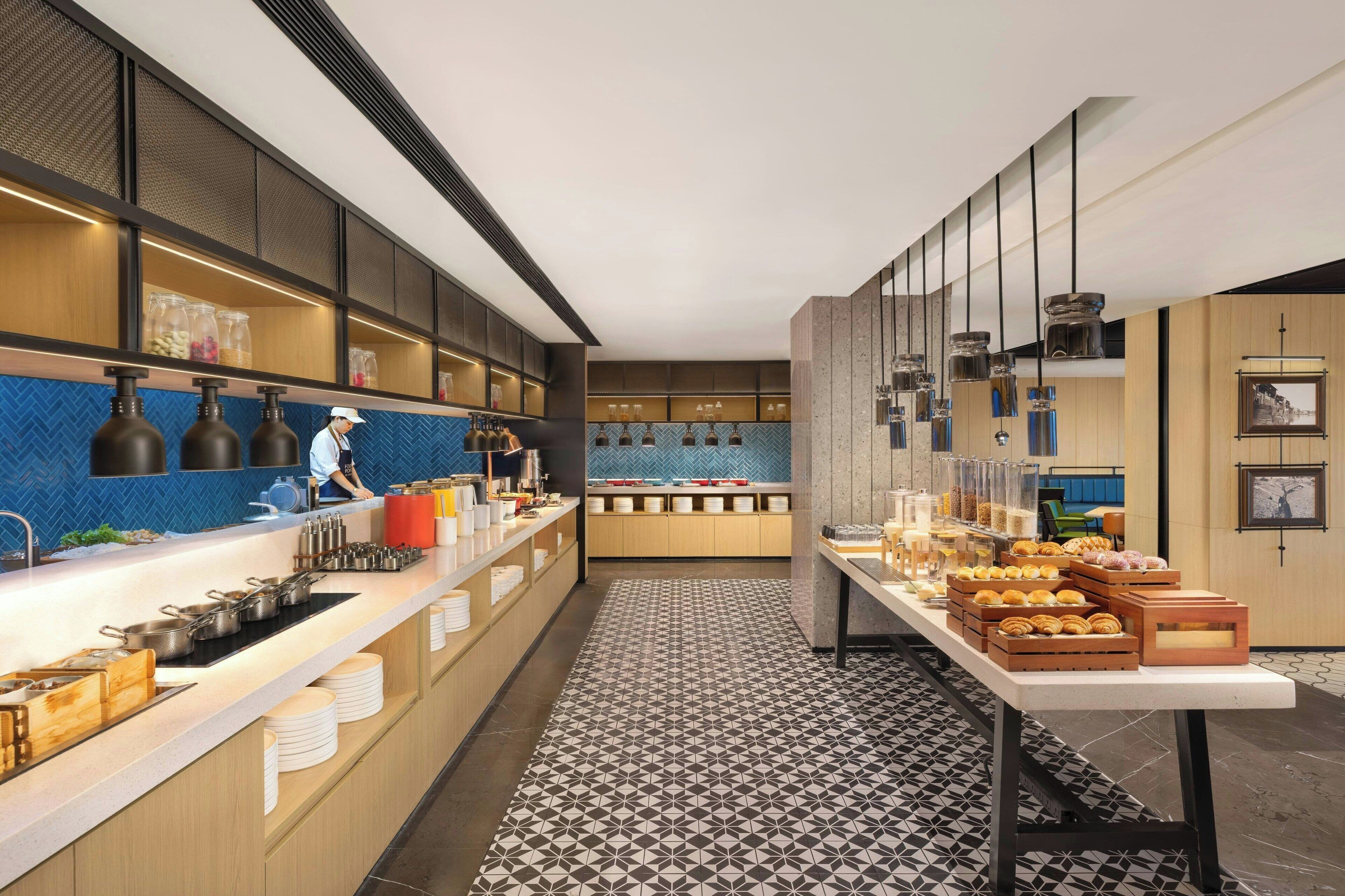Une cuisine moderne avec un long comptoir, divers ustensiles de cuisine et une personne qui travaille.