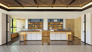 Un espace d’accueil moderne avec un plafond au design géométrique, un comptoir central doté de vitrines et un sol à motifs.