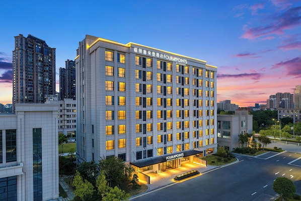 A multi-story hotel with a modern facade, large windows, and a well-lit entrance area.