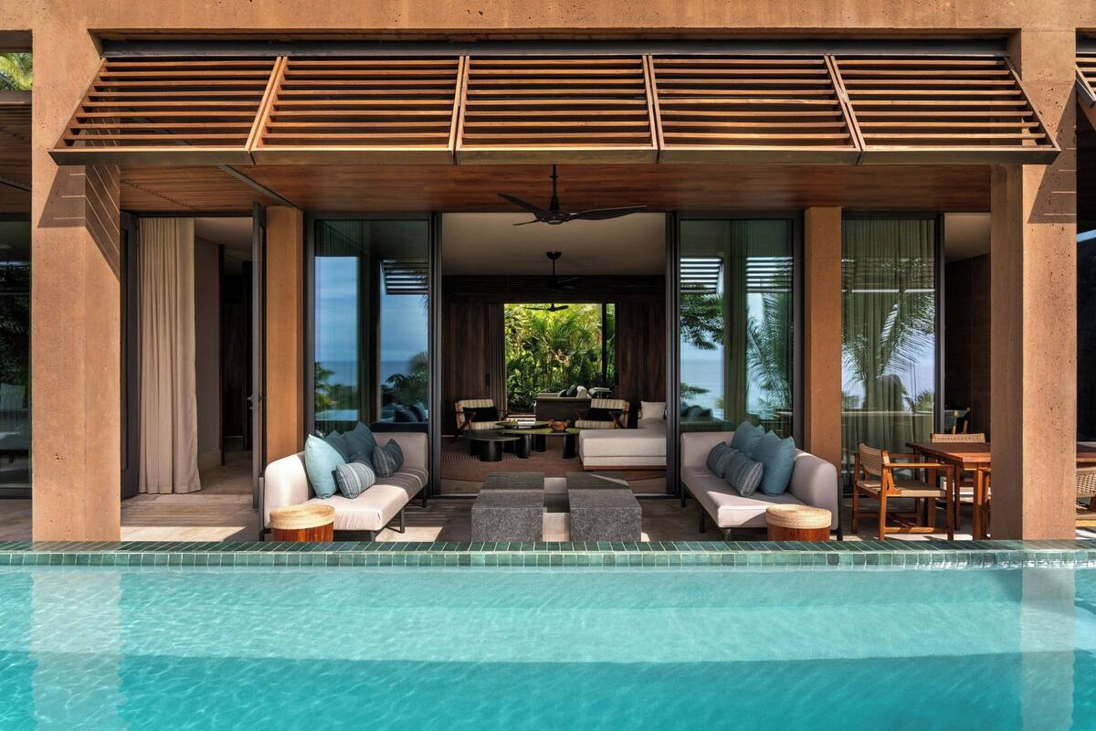 A modern outdoor pool area with a seating arrangement and a view of the outdoors.