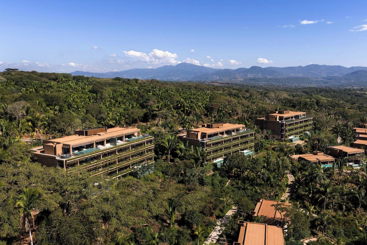 Un resort con varias edificaciones, piscinas y abundante vegetación.