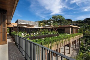 A modern hotel with outdoor seating, a covered area, and a view of surrounding buildings.