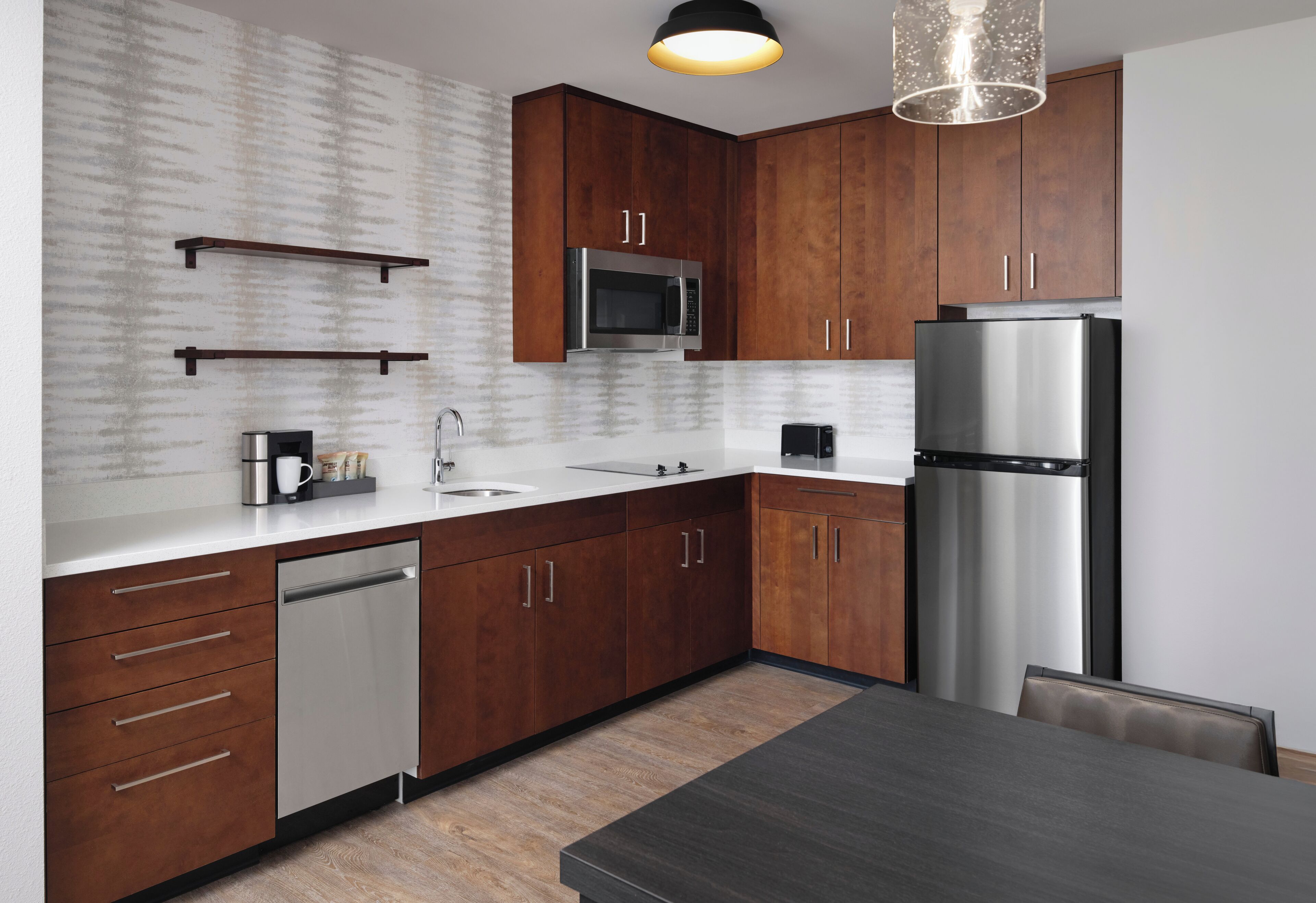 A modern kitchen with wooden cabinets, stainless steel appliances, and a dark countertop.