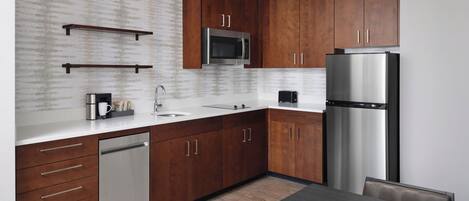 A modern kitchen with wooden cabinets, stainless steel appliances, and a dark countertop.