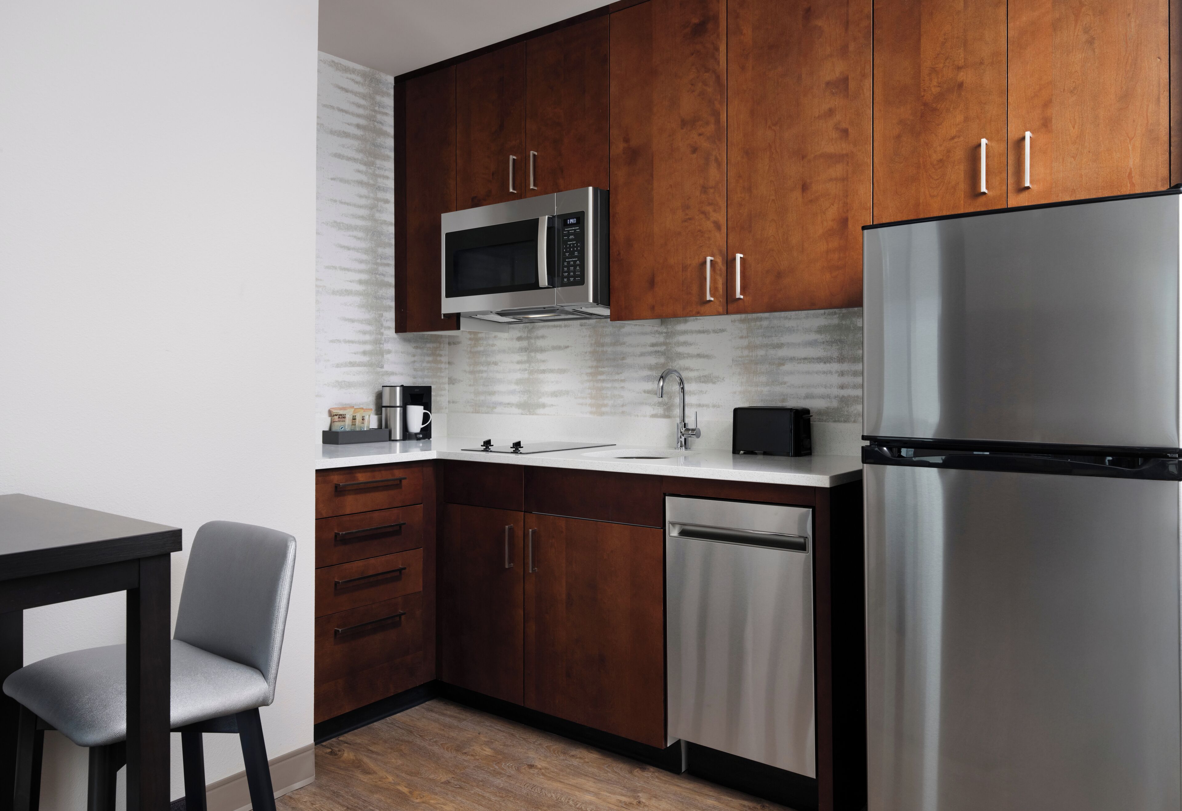 Een moderne keuken met houten kastjes, een roestvrijstalen koelkast, een magnetron en een vaatwasser.