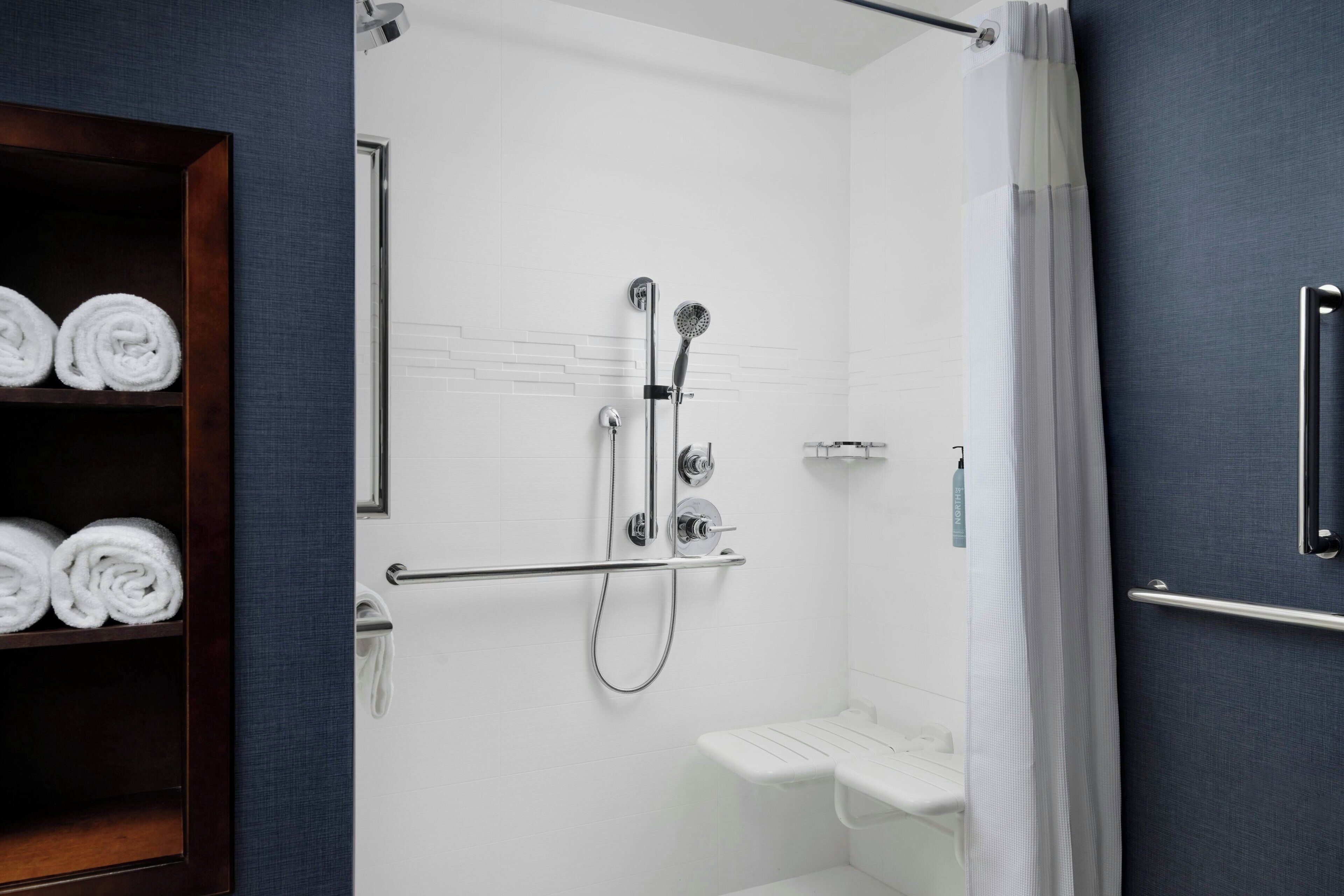 A modern bathroom with a shower, a towel rack, and a toilet.