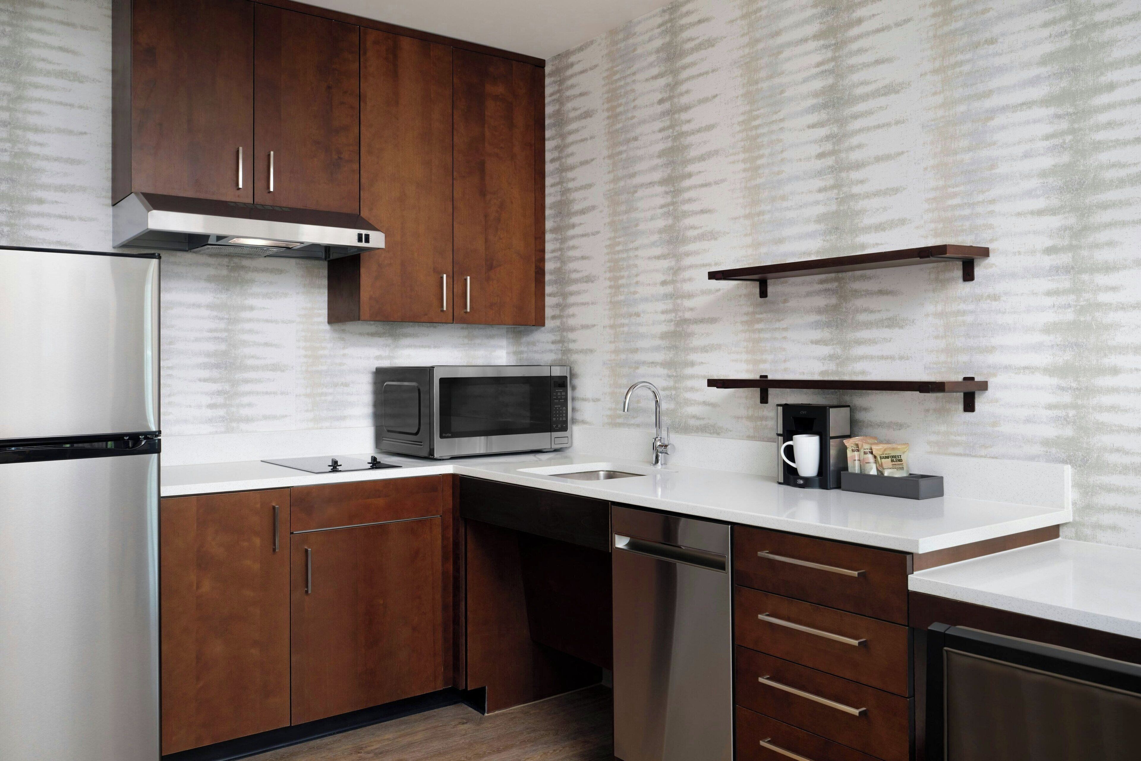 A modern kitchen with wooden cabinets, stainless steel appliances, and a white countertop.