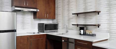 A modern kitchen with wooden cabinets, stainless steel appliances, and a white countertop.