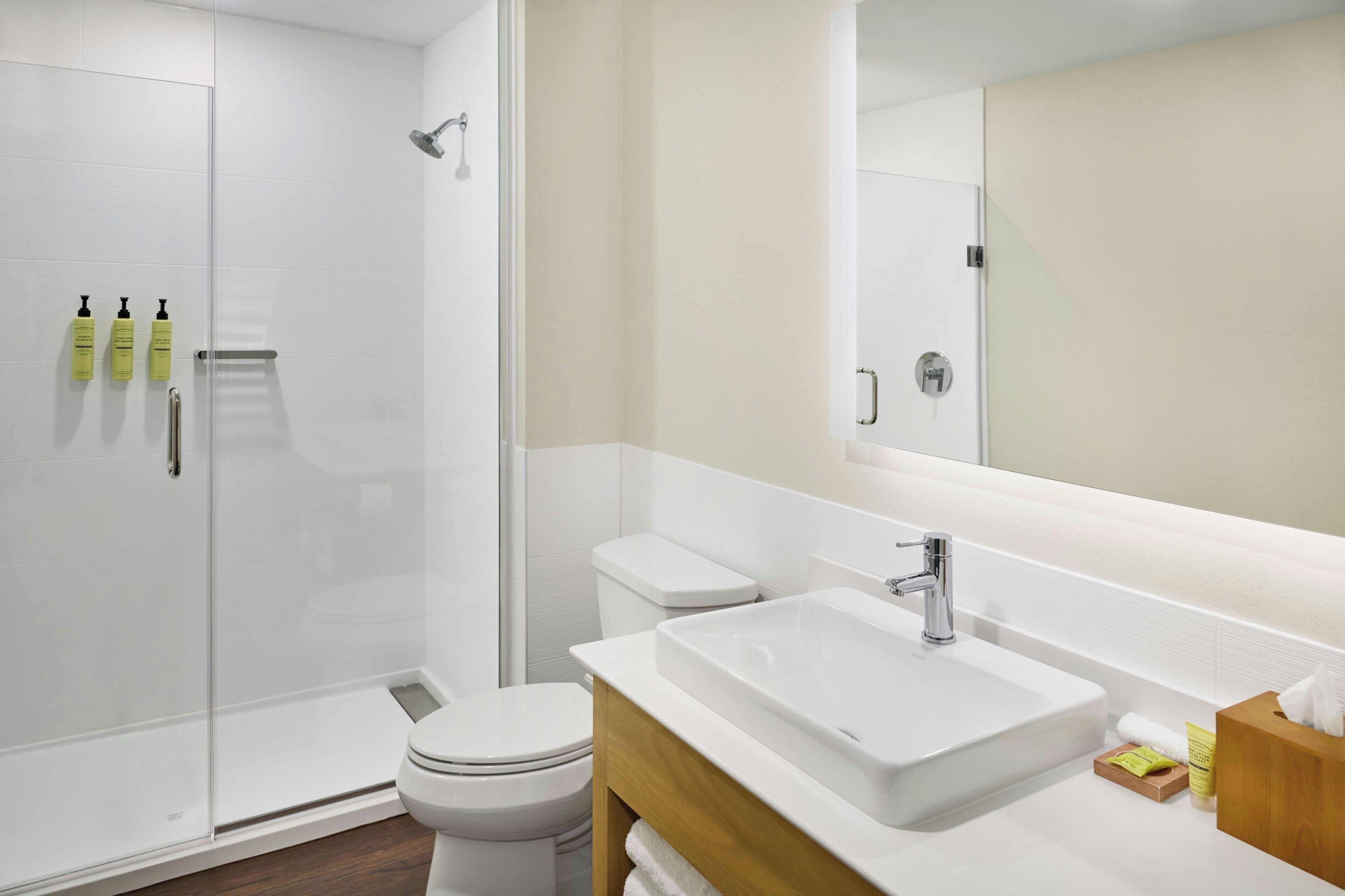 A modern bathroom with a glass-enclosed shower, a white toilet, and a vanity with a sink and mirror.