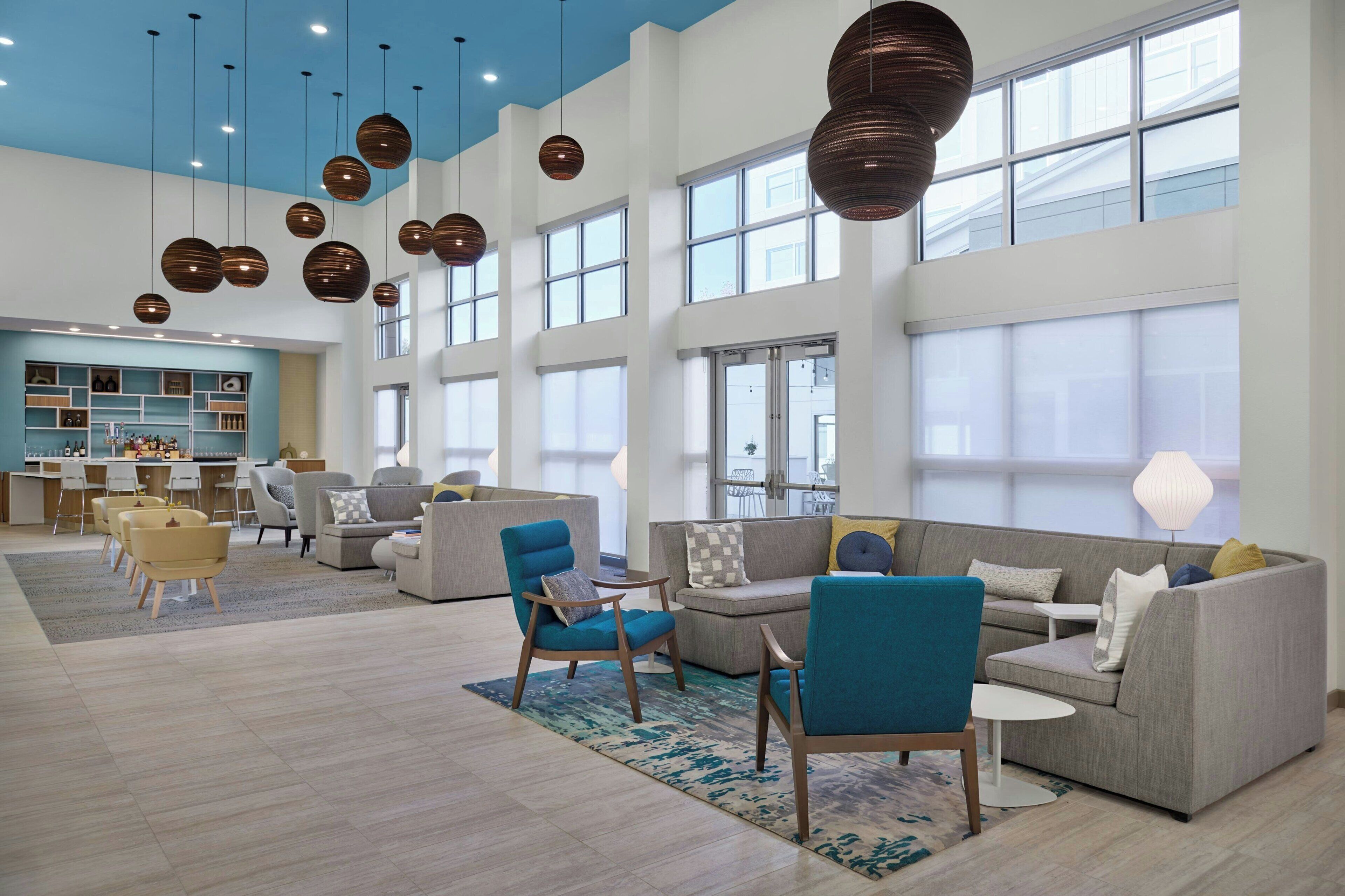 A spacious living area with multiple seating options, large windows, and modern pendant lighting.