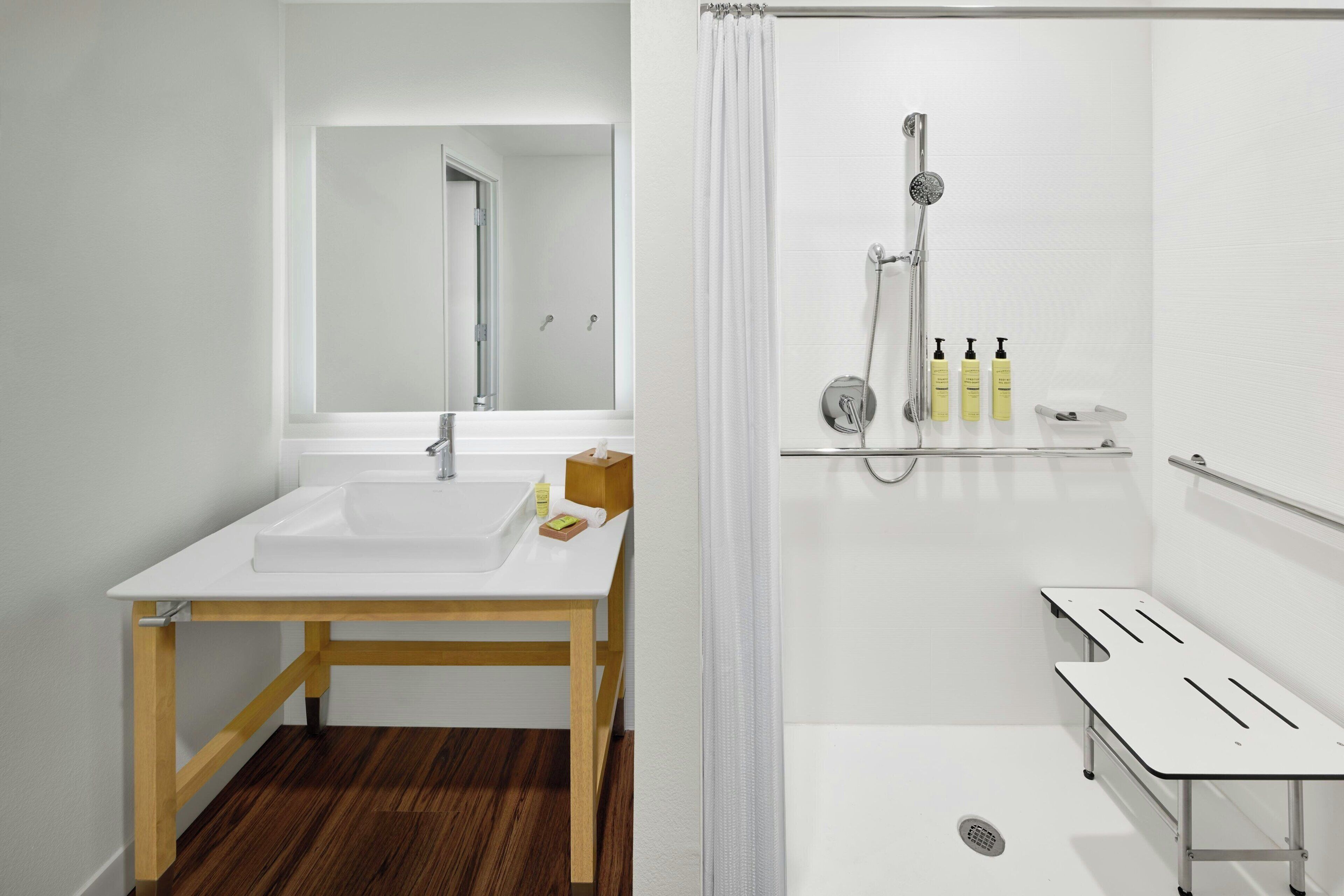 Casa de banho moderna com lavatório branco, espelho e área de duche.