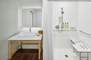 Casa de banho moderna com lavatório branco, espelho e área de duche.