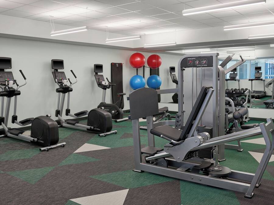 A gym with treadmills, ellipticals, a weight machine, and exercise balls.