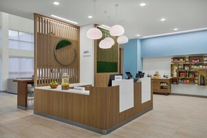 A reception desk with a wooden finish, a green wall with a circular design, and a reception area with a computer and phone.