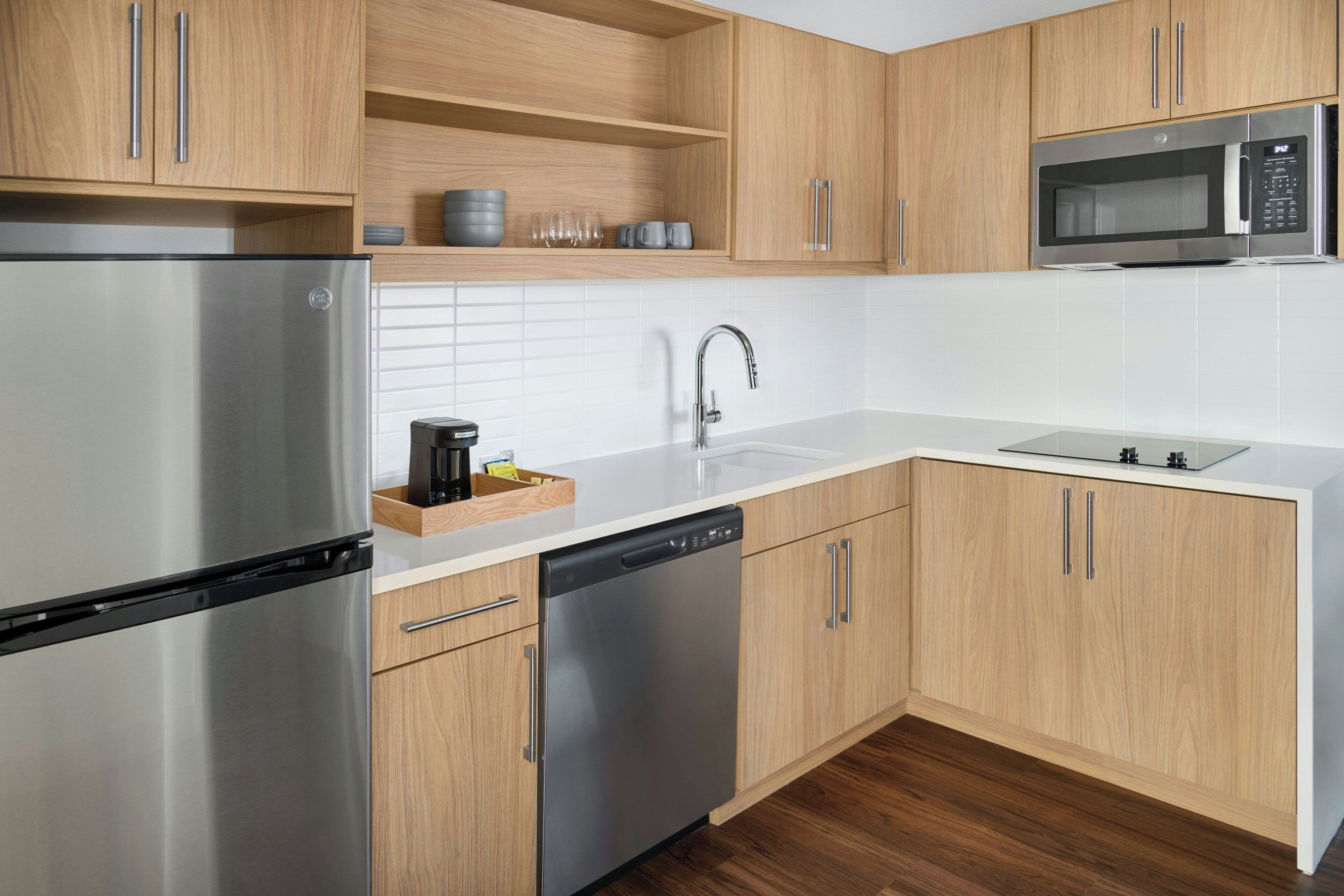 A modern kitchen with stainless steel appliances, wooden cabinets, and a white countertop.
