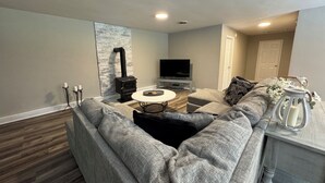 A modern living room with a sectional sofa, a fireplace, a TV, and a small round table. - Escape to Comfort in Newport (Newport)