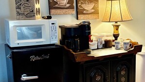 Une petite cuisine équipée d’un réfrigérateur, d’un four à micro-ondes, d’une machine à café et d’un espace dédié à la préparation du café.