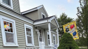 Une maison avec un porche, un petit jardin et un drapeau.
