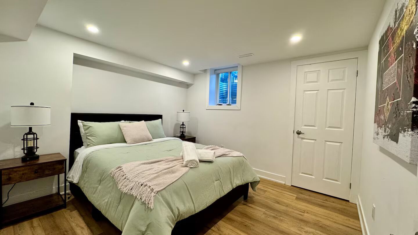 A bedroom with a bed, bedside tables, a window, and a door.