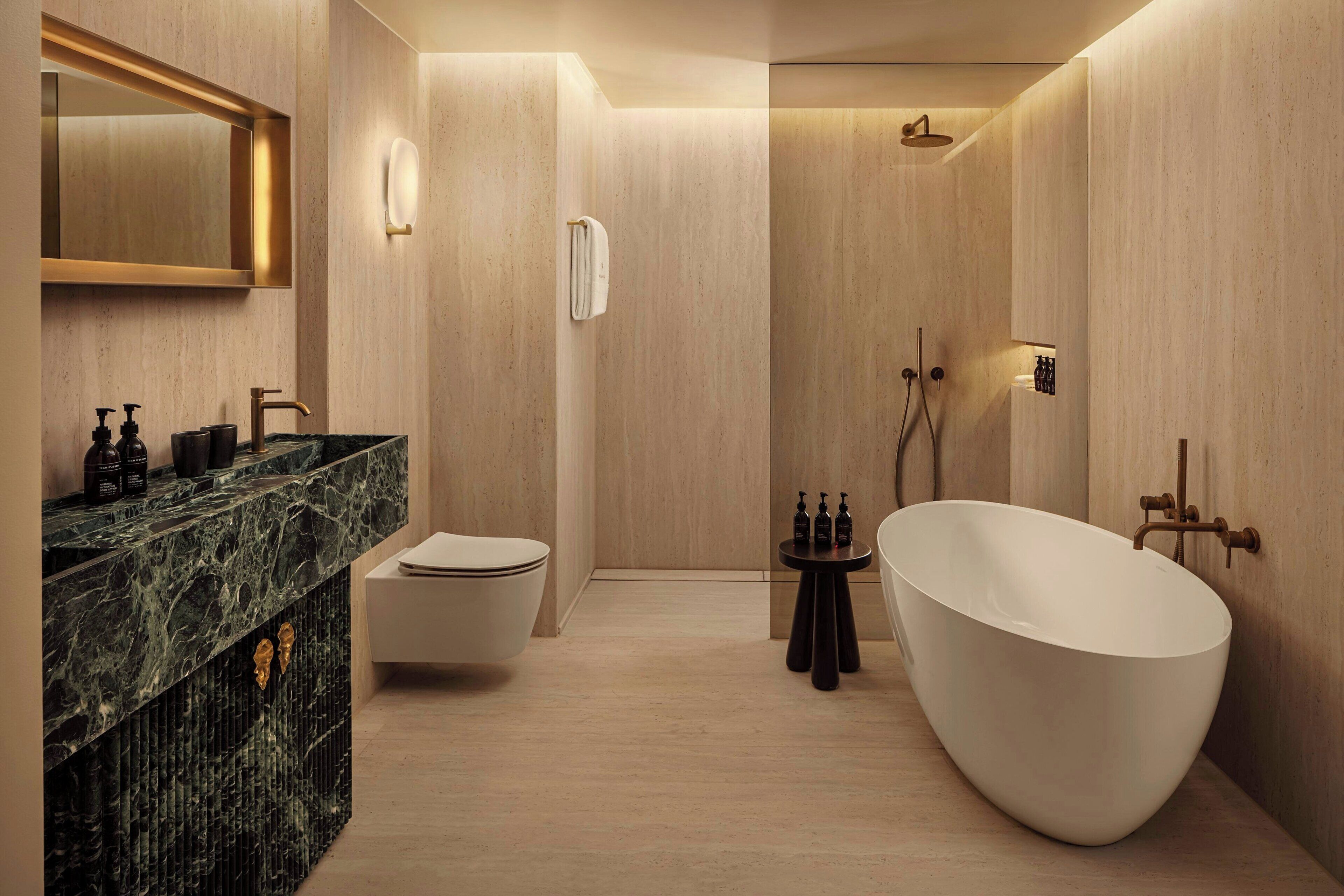 Ein modernes Badezimmer mit einer freistehenden Badewanne, einer Toilette und einem Waschtisch mit Marmorplatte.