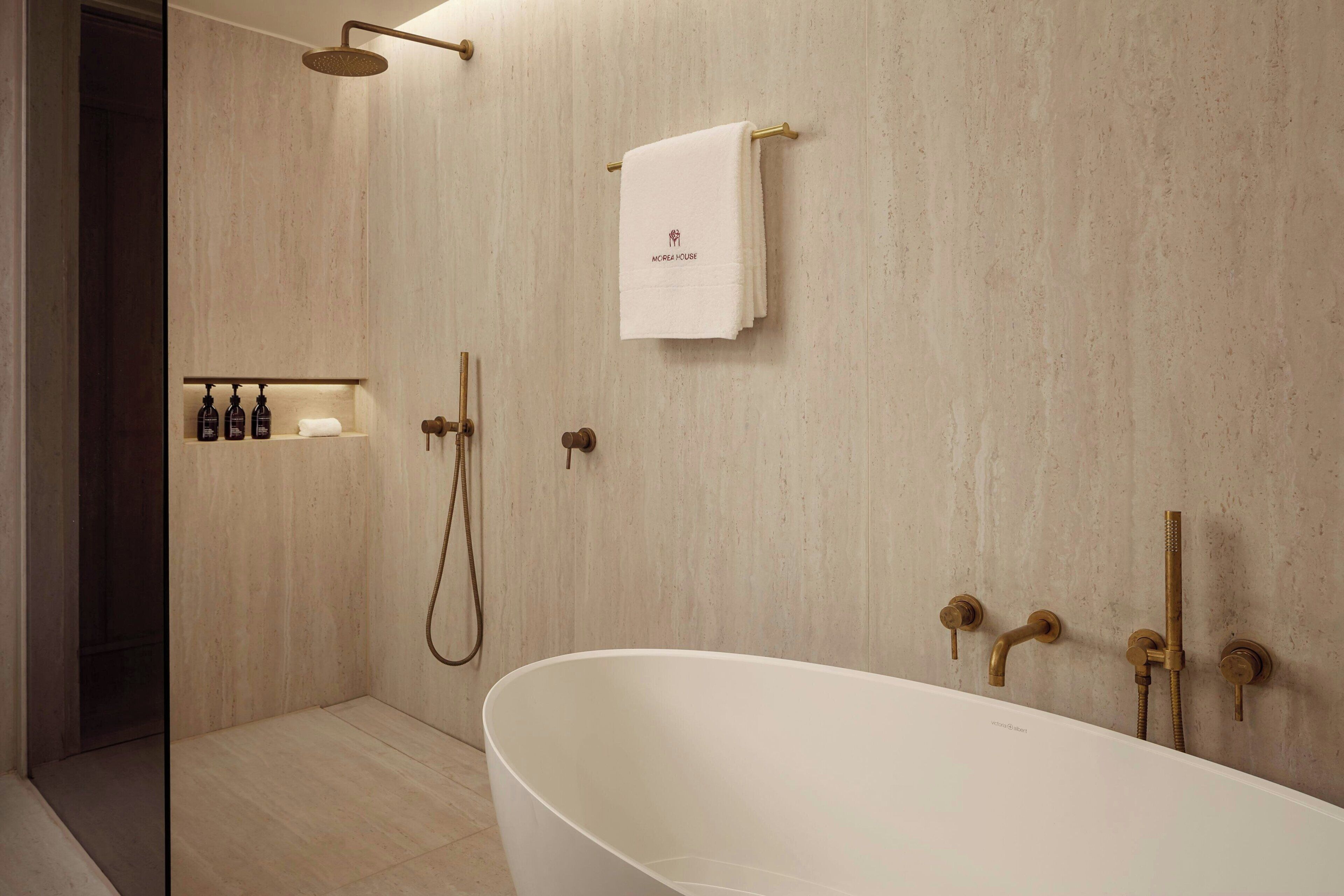 A modern bathroom with a freestanding bathtub, a shower with a handheld showerhead, and a towel rack with a towel hanging on it.