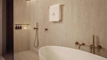 A modern bathroom with a freestanding bathtub, a shower with a handheld showerhead, and a towel rack with a towel hanging on it.