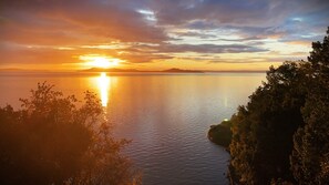 A coastal sunset view with calm waters and distant land.