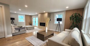 A modern living room with a sofa, ottoman, coffee table, and a floor lamp.