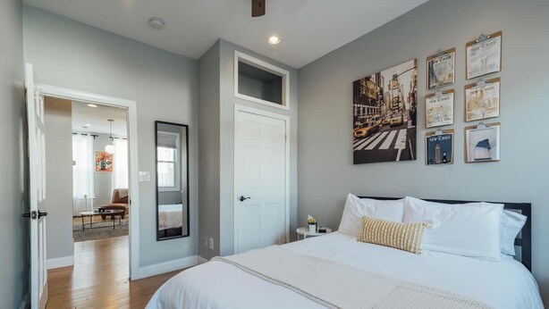 Un dormitorio con una cama grande, una puerta que da a otra habitación y una pared con cuadros.