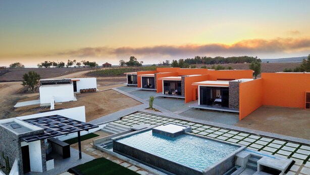 Un complexe hôtelier moderne composé de plusieurs bâtiments aux couleurs orangées, doté d’une piscine et offrant en toile de fond un paysage désertique.