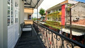 Un balcon doté d’une balustrade en fer forgé noir, une porte blanche avec des panneaux de verre et un banc.