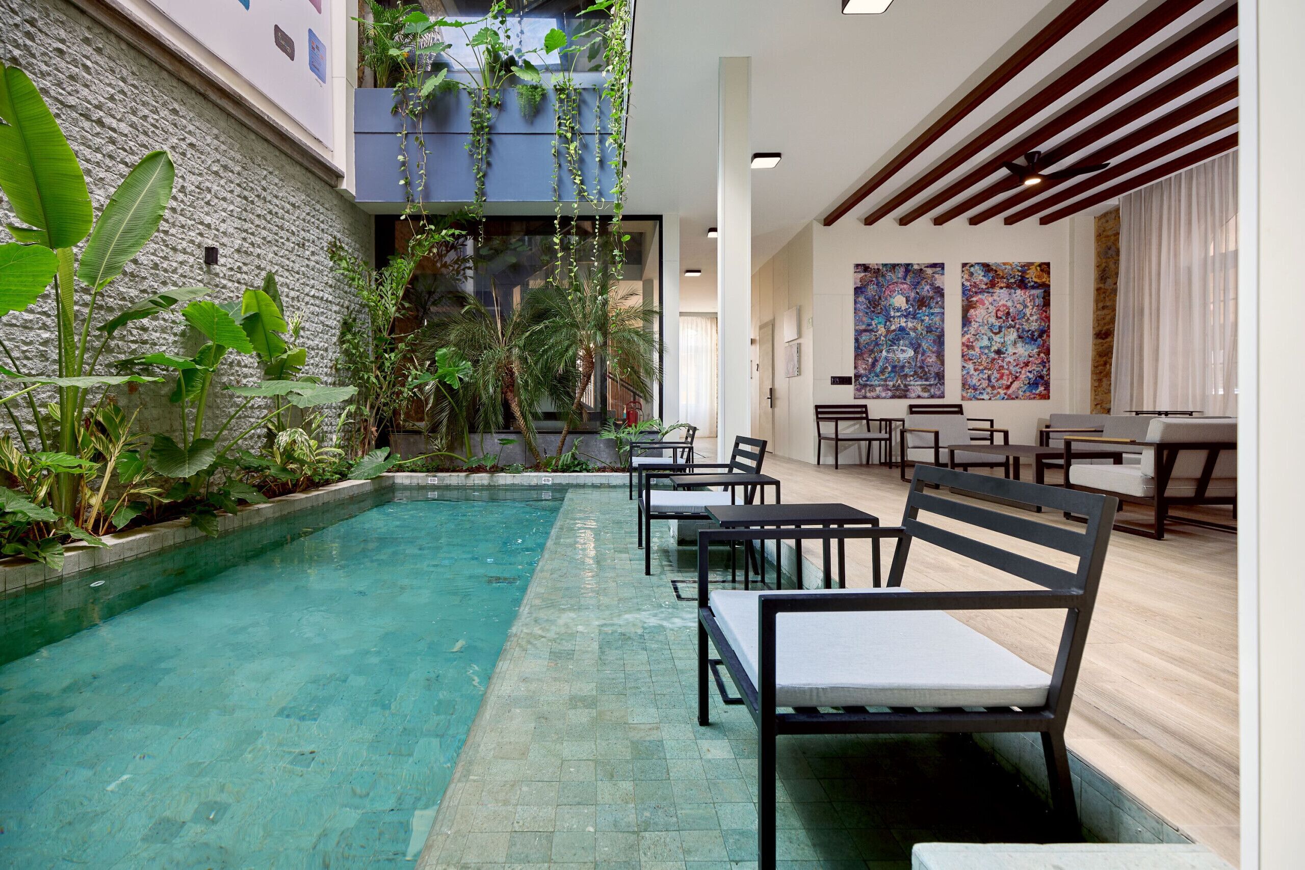 Un espace piscine agrémenté de chaises longues, d’un mur en pierre et de plantes d’intérieur.