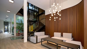 A modern lobby with a staircase, seating area, and a hanging light fixture. - Exclusively designed room CG8 (Ciudad de Panamá)