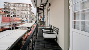 A balcony with a view of a cityscape, featuring buildings with balconies and a tiled roof. - Exclusively designed room CG8 (Ciudad de Panamá)