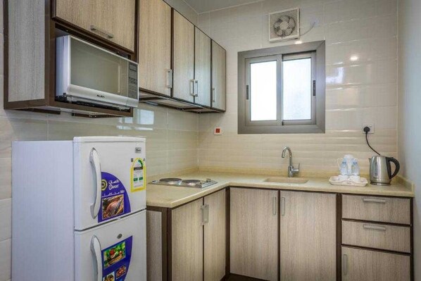 Une cuisine avec des meubles de rangement en bois, un réfrigérateur blanc, une fenêtre et un évier.