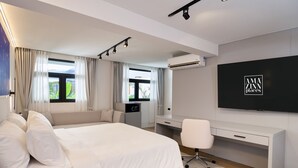 A modern hotel room with a large bed, a desk, and a TV.