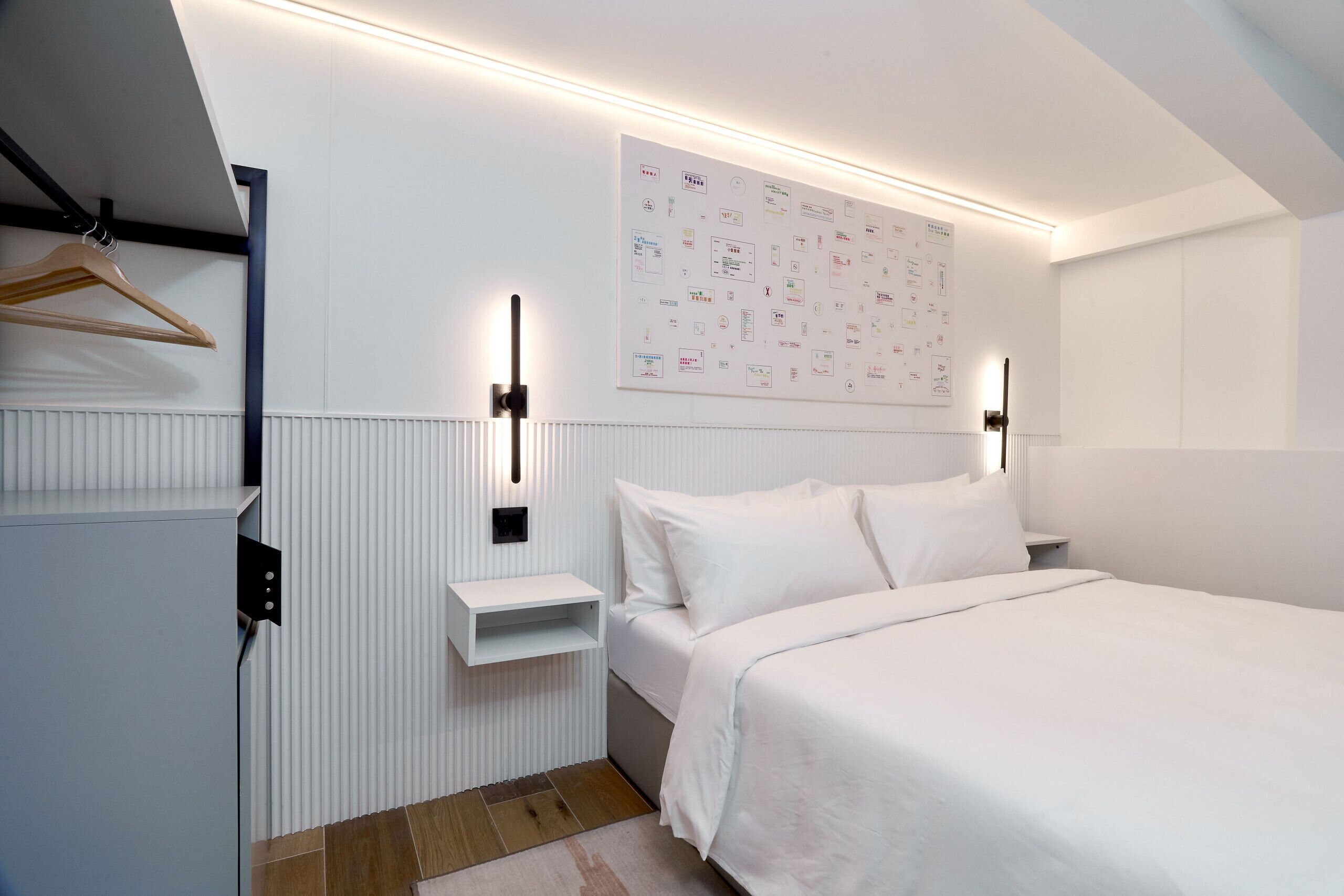 A modern bedroom with a bed, bedside tables, and a wall-mounted light fixture.