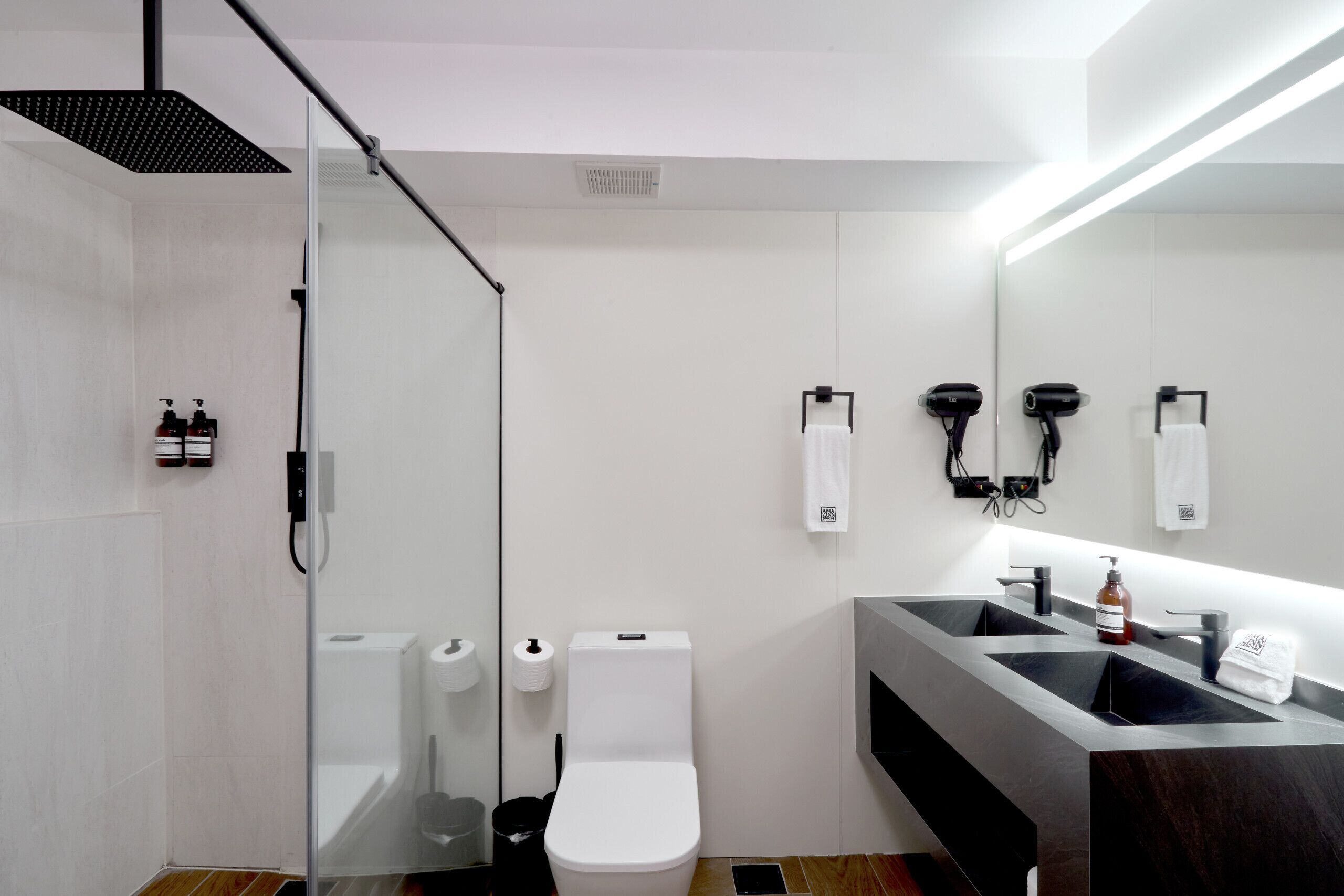 A modern bathroom with a glass shower enclosure, a toilet, a sink with a mirror, and a towel rack.