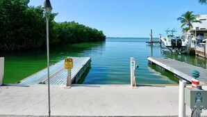 A marina with a dock, a sign indicating no wake zone, and a clear view of the water. - Charming 2-bedroom campground in Key Largo with AC (Key Largo)