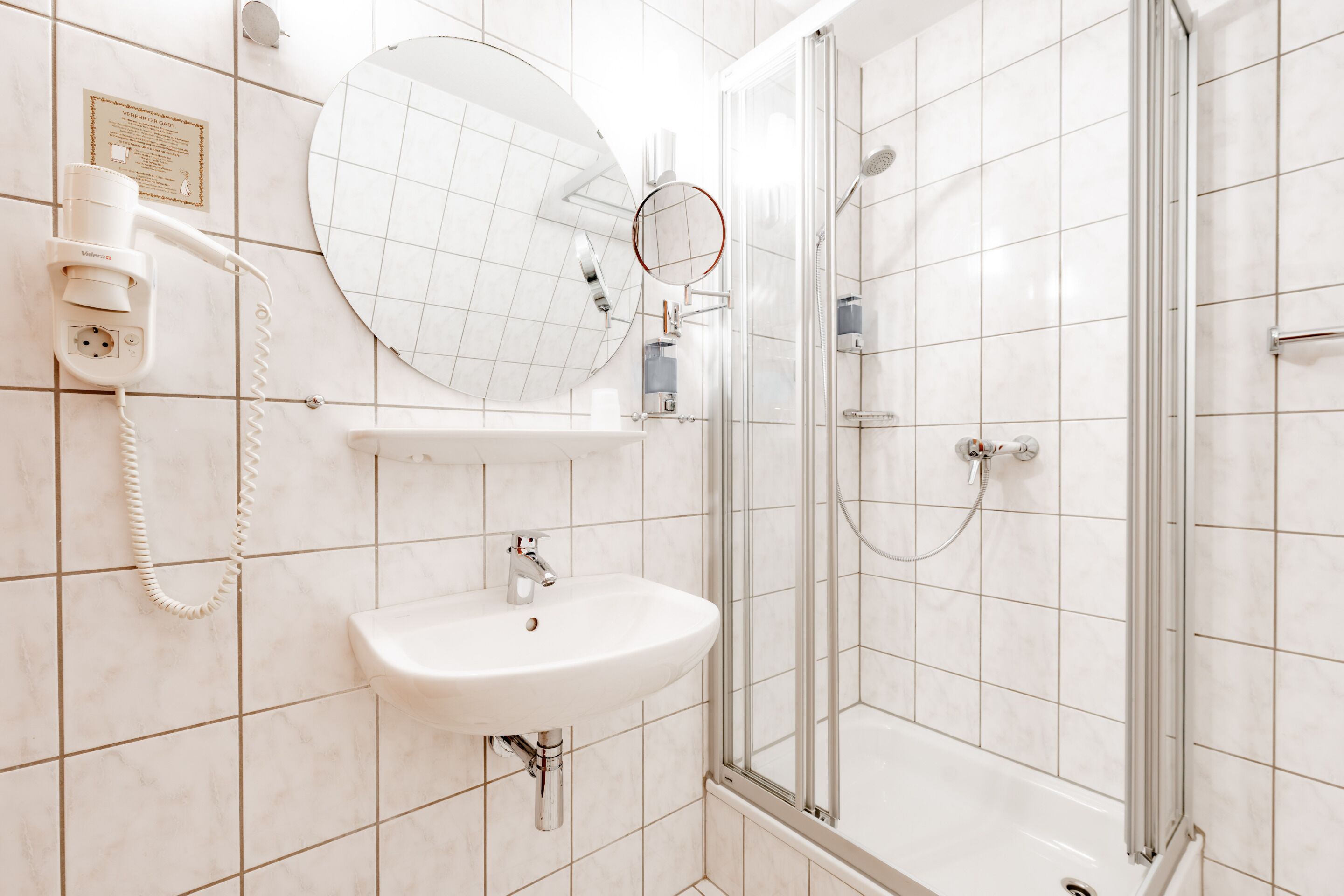 Un baño con lavabo, espejo y ducha.