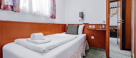 Una habitación de hotel con una cama bien hecha, una mesita de noche con una lámpara y un espejo.
