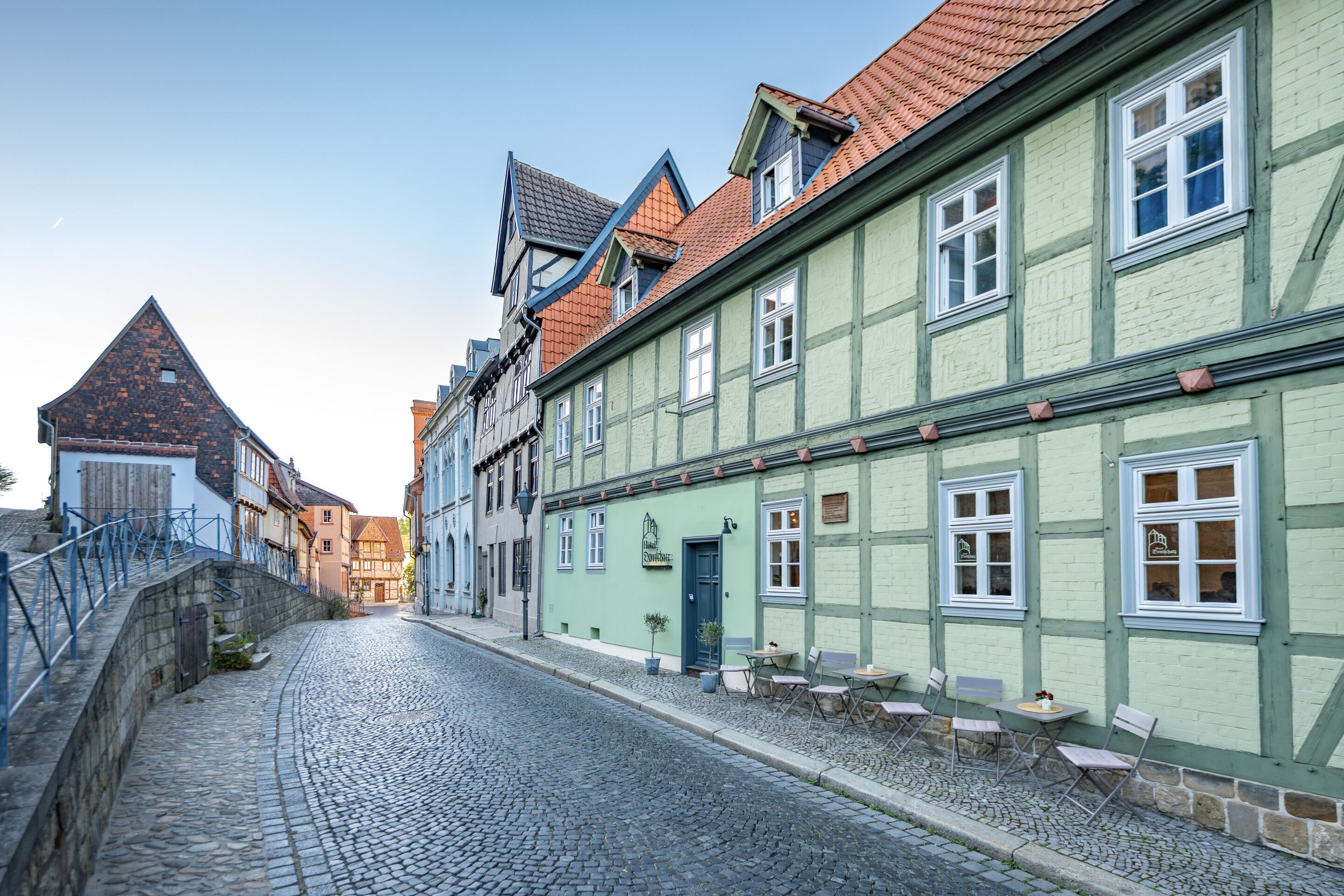 A cobblestone street lined with traditional half-timbered buildings, some with outdoor seating.